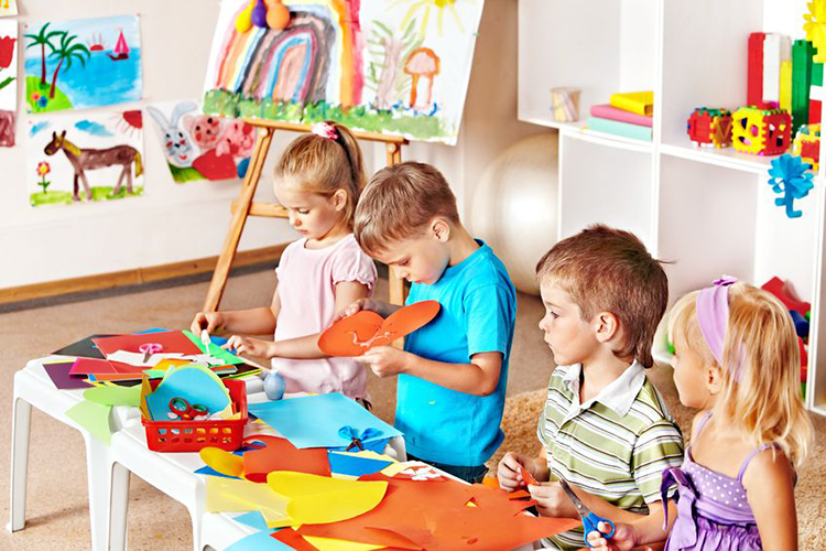 Behavioural difficultiesv- Four children play arts and crafts in nursery