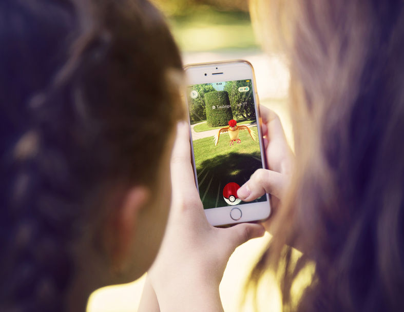 : little girls playing a pokemon go game outdoors. pokemon go is a location-based augmented reality mobile game.