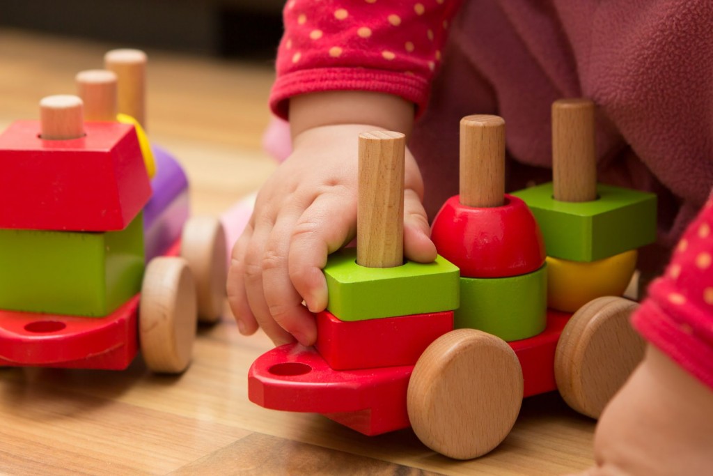 Cognitive development – baby hand playing with wooden toys