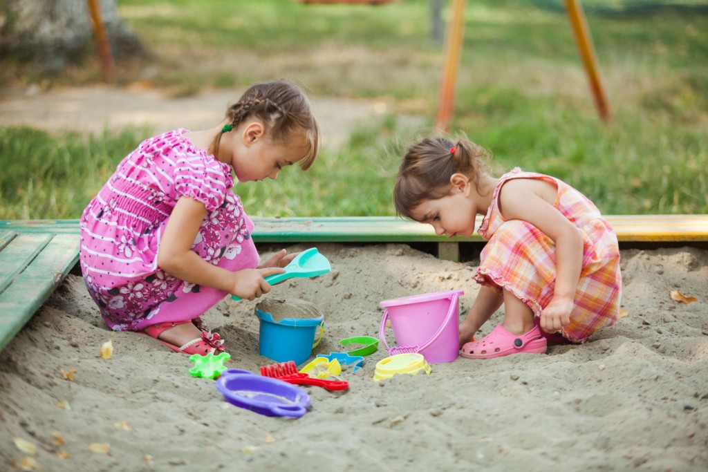 Two girls play in the sandbox